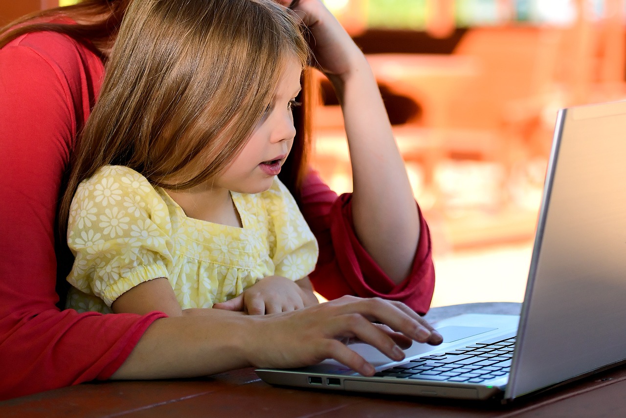 child on mothers lap looking at a laptop