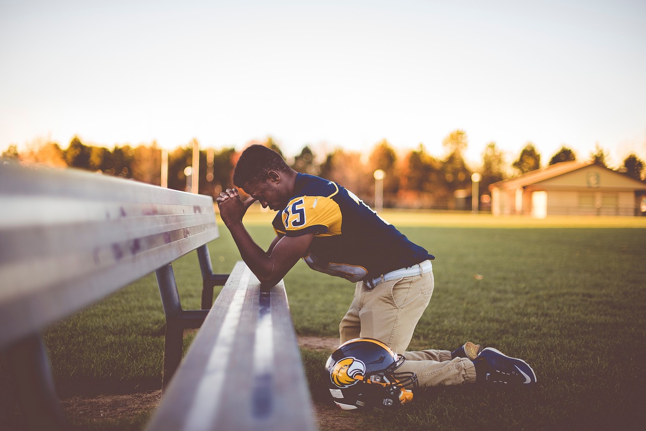 athelete worried and kneeling at a bench