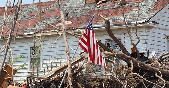 A US American flag rises above a home ruined by a deadly EF-5 tornado.